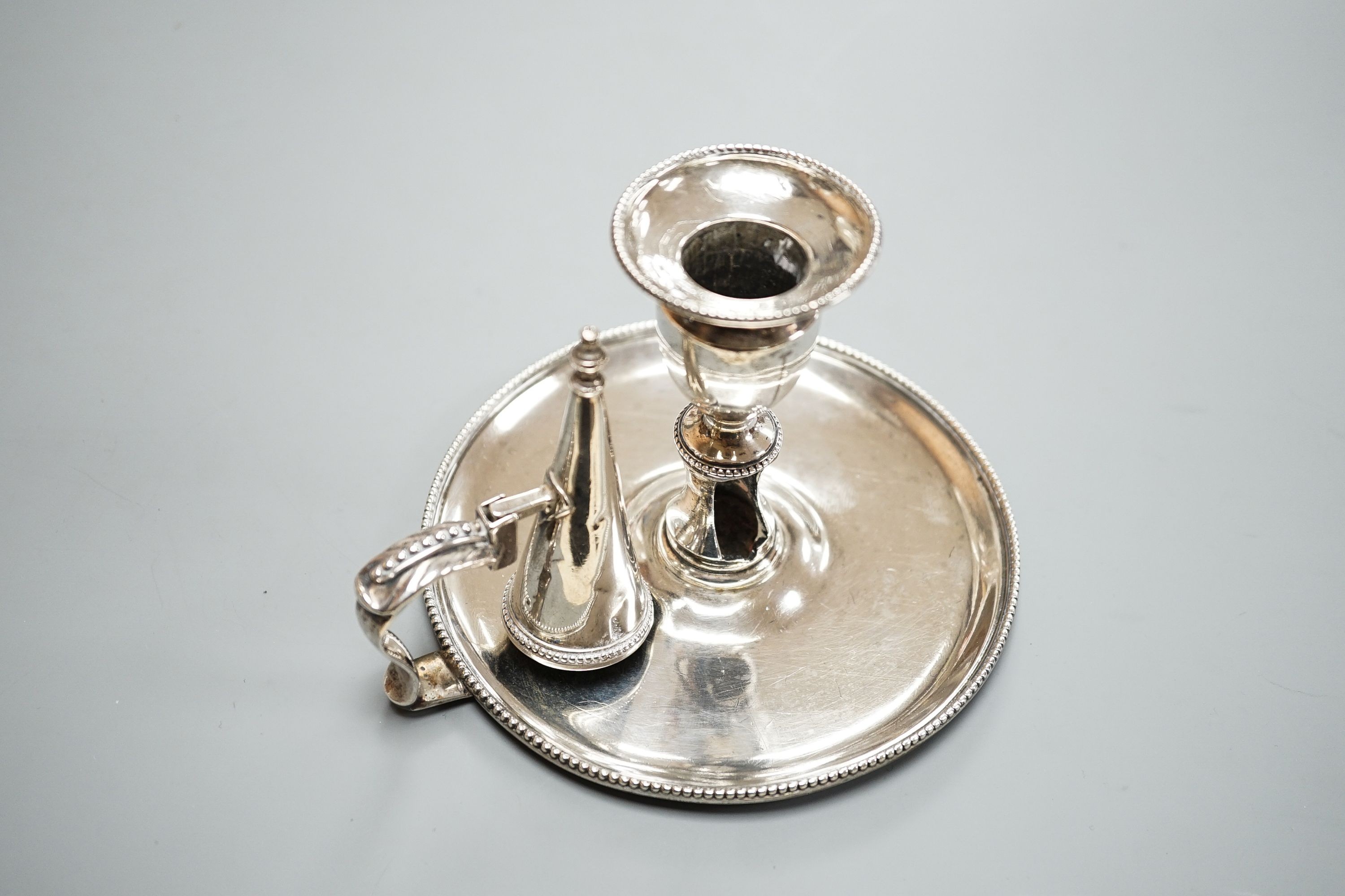 A George III silver chamberstick, by John Arnell, with beaded border and matching sconce and snuffer, London, 1784, diameter 12.8cm, 8oz (a.f.).